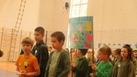 12. Grupa dzieci idzie po hali, niosą transparenty z hasłami, z przodu nauczycielka.